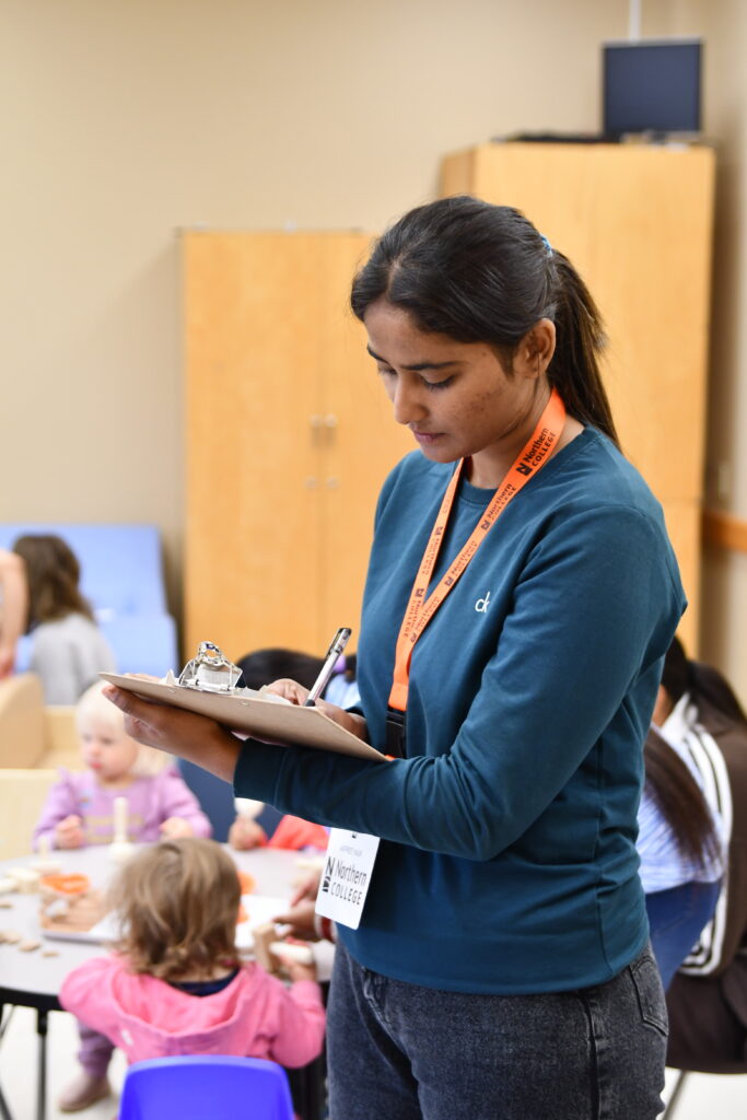 Early Childhood Education student with clipboard in children's play lab