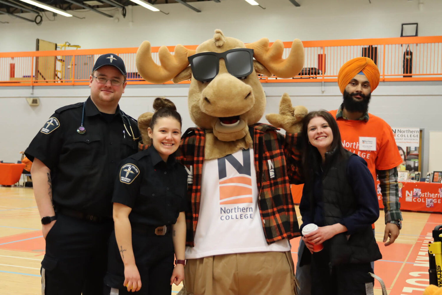 Northern college staff and students with moose mascot in timmns campus gym for open house event